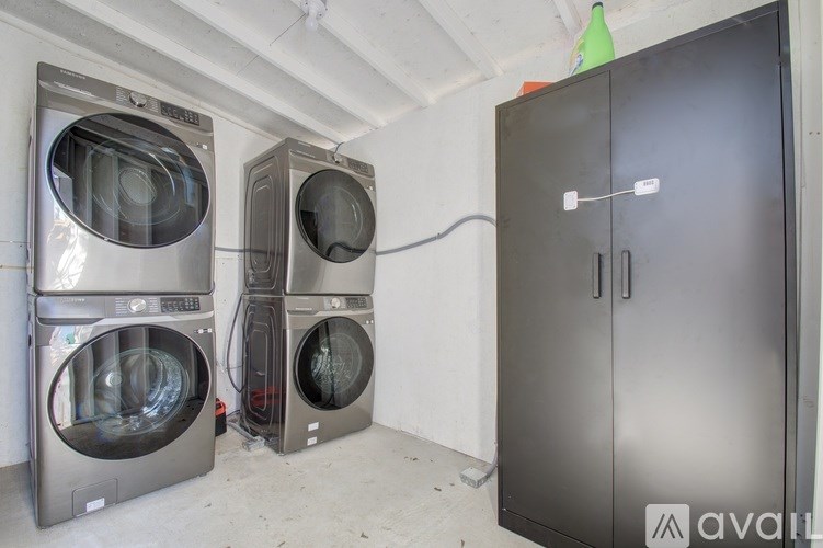 A room with a washing machine, dryer, and a cabinet.