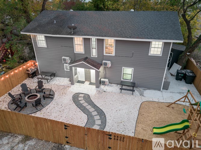 A house with a grey exterior and a brown roof with a patio and a slide.