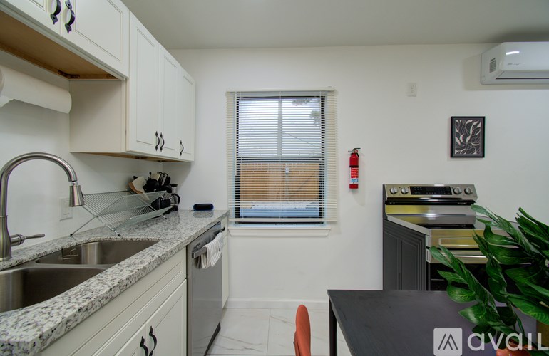 A kitchen with a sink, stove, and a window with blinds.