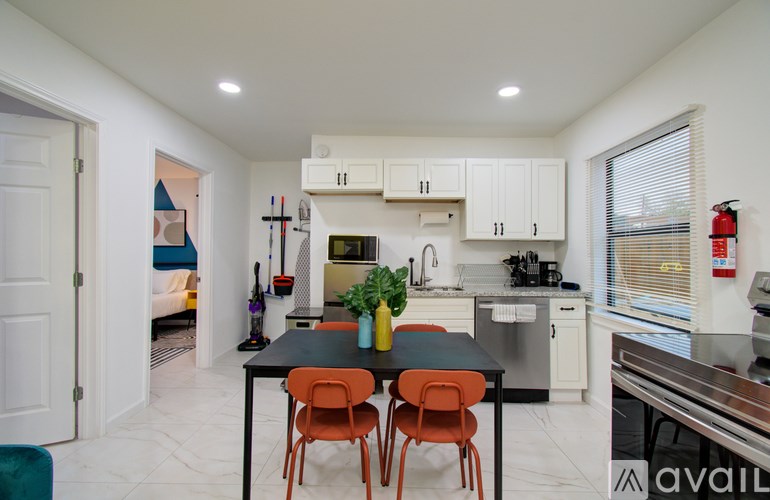 A kitchen with a black table and orange chairs.