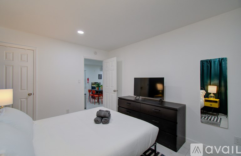 A bedroom with a bed, desk, and television.