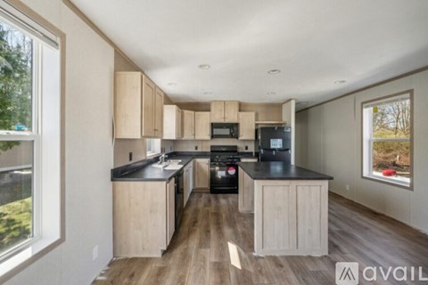 A kitchen with wooden cabinets and black countertops is available for rent.