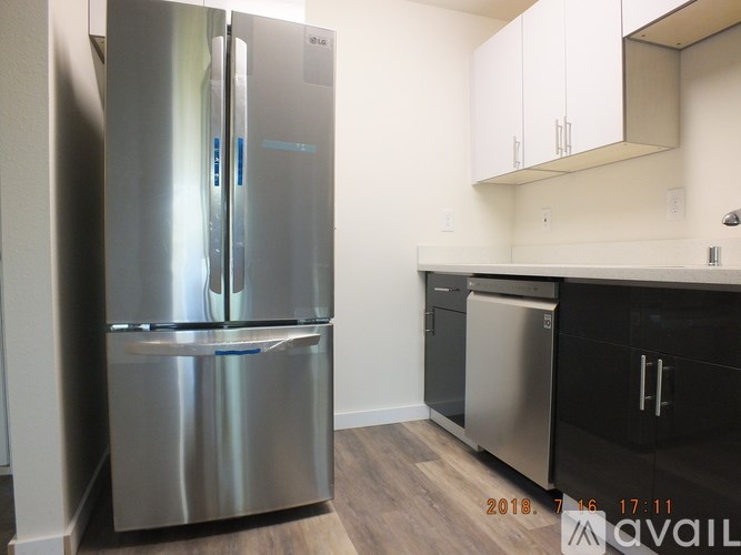 A stainless steel refrigerator stands in a kitchen with white cabinets.