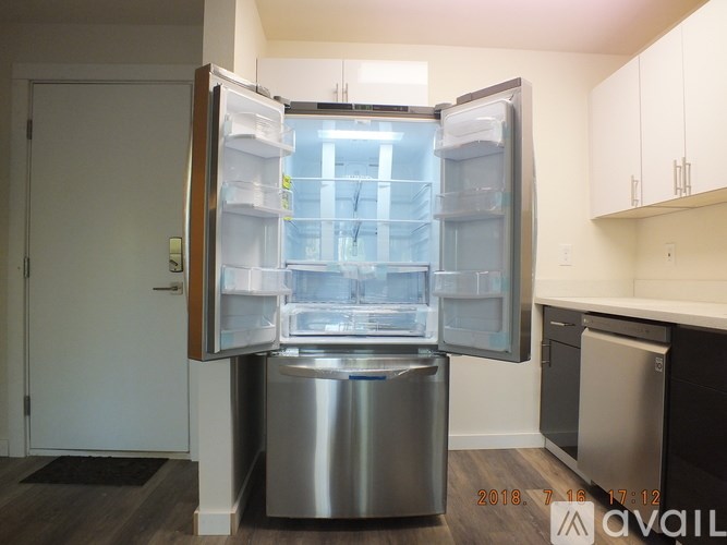 A modern kitchen with a stainless steel refrigerator and a trash can.