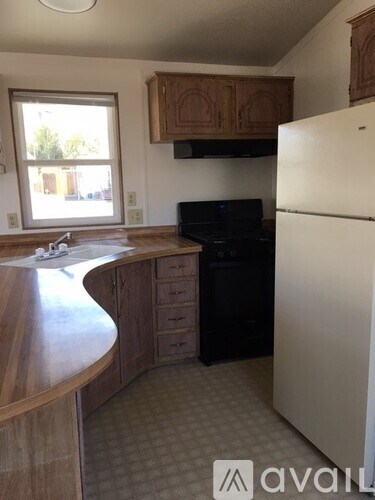 A kitchen with a white refrigerator, black stove, and wooden cabinets.