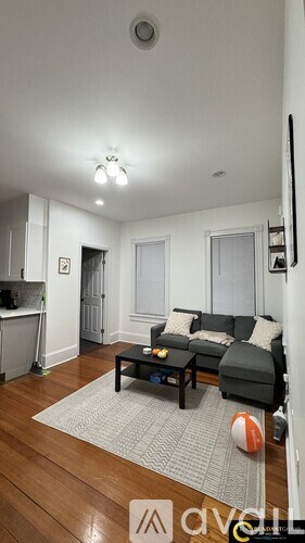 A living room with a black couch and a grey rug.