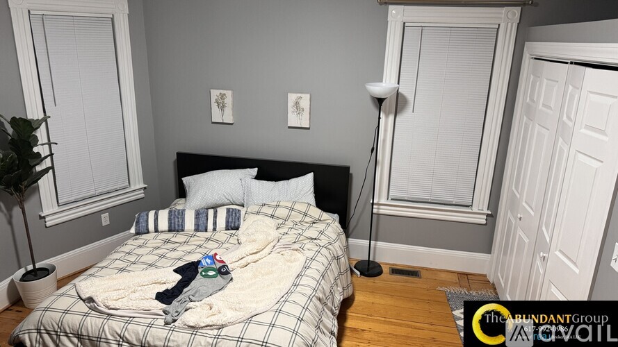 A bedroom with a bed covered in a plaid comforter and a pair of shoes on top.