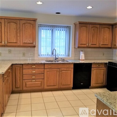 A kitchen with wooden cabinets and a black dishwasher.
