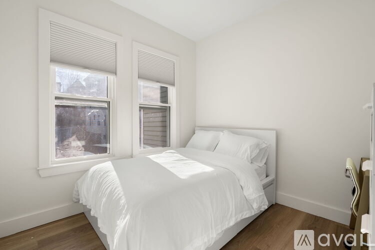 A white bedroom with a large bed and two windows.