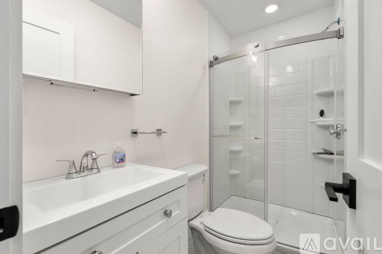A white bathroom with a toilet, sink, and shower.