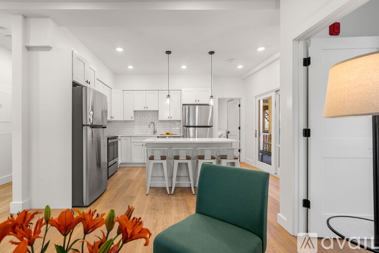 A kitchen with a green chair and a vase of red flowers.