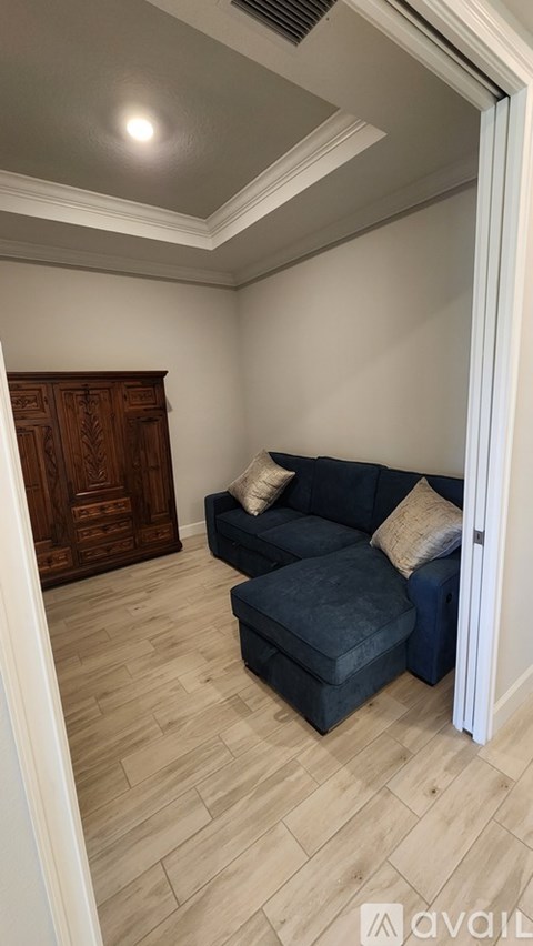 A living room with a dark blue couch and a wooden cabinet.