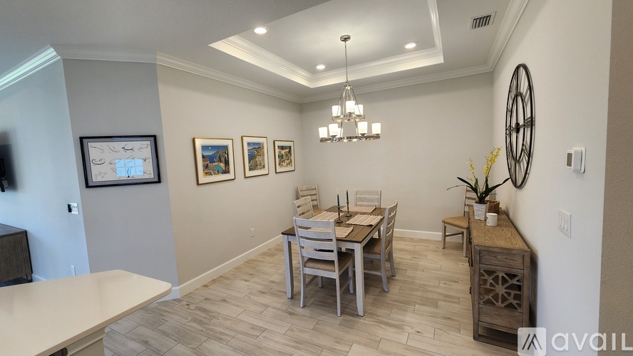 A dining room with a table set for four and a chandelier hanging from the ceiling.