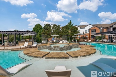 A large outdoor pool with a hot tub and lounge chairs.