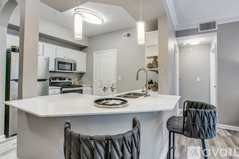 A modern kitchen with a white island and grey chairs.
