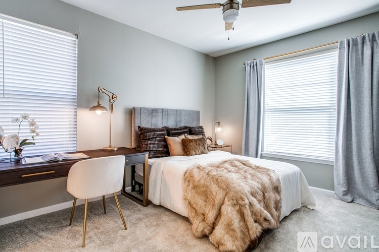 A bedroom with a large bed, a desk with a chair, and a ceiling fan.