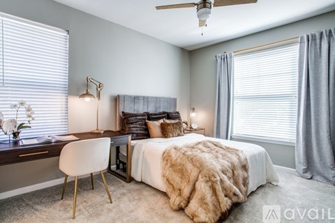A bedroom with a large bed, a desk with a chair, and a ceiling fan.