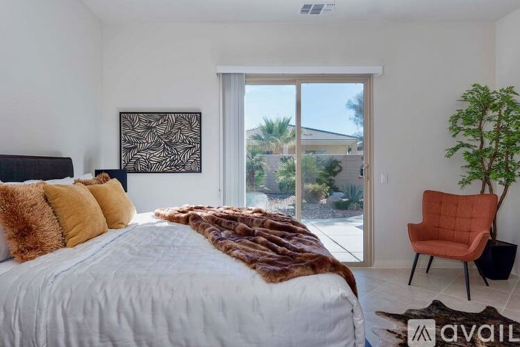 A bedroom with a large bed, a chair, and a plant.