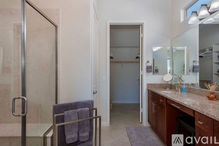 A bathroom with a glass shower door and a sink with a mirror above it.