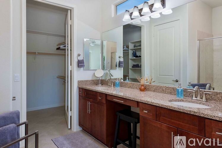 A bathroom with a vanity, a mirror, and a chair.