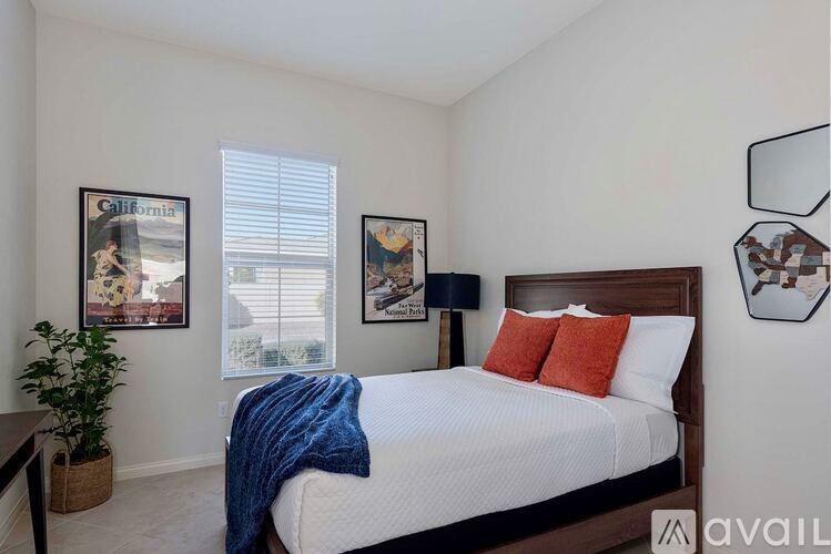 A bedroom with a bed, a potted plant, and pictures on the wall.