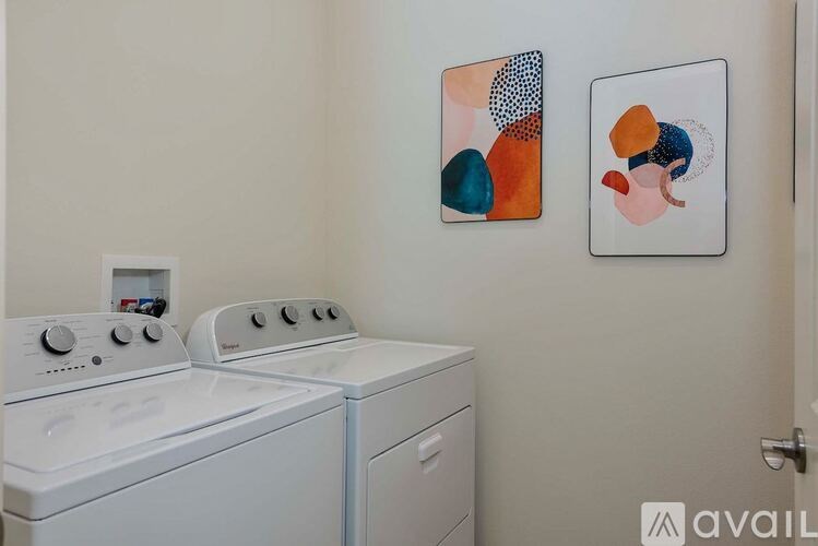Two white washing machines in a laundry room with abstract art on the wall.