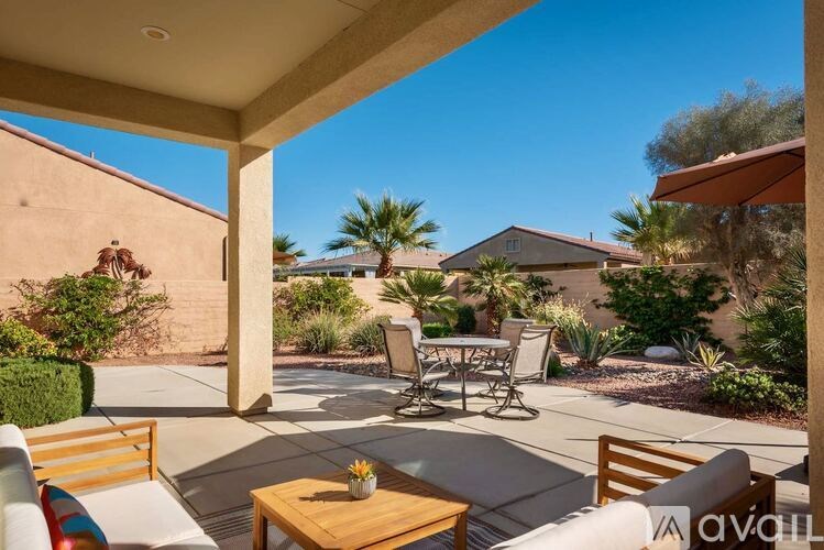 A patio with a table and chairs is surrounded by a garden.
