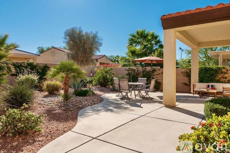 A patio with a table and chairs is surrounded by a garden.