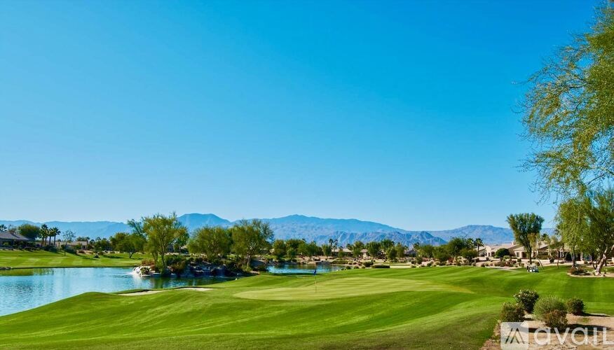 A golf course with a lake and mountains in the background.