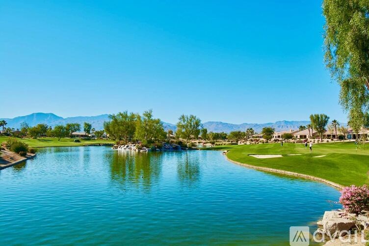A serene golf course with a lake and mountains in the distance.