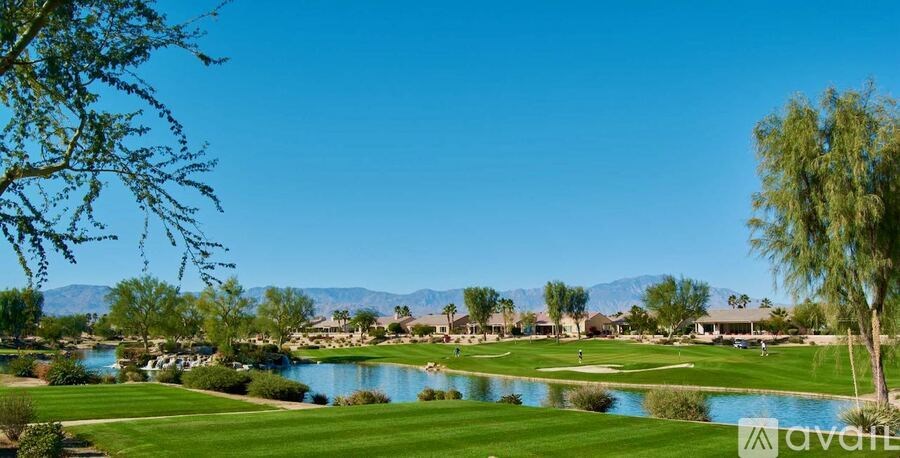 A golf course with a lake and mountains in the background.
