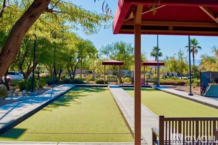 A park with a red canopy and a green lawn.