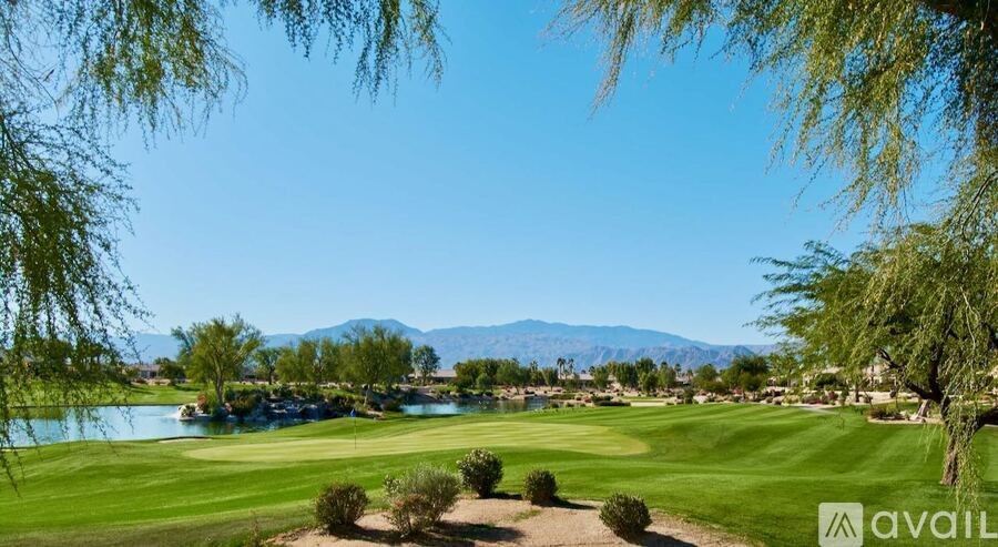 A golf course with a lake and mountains in the background.
