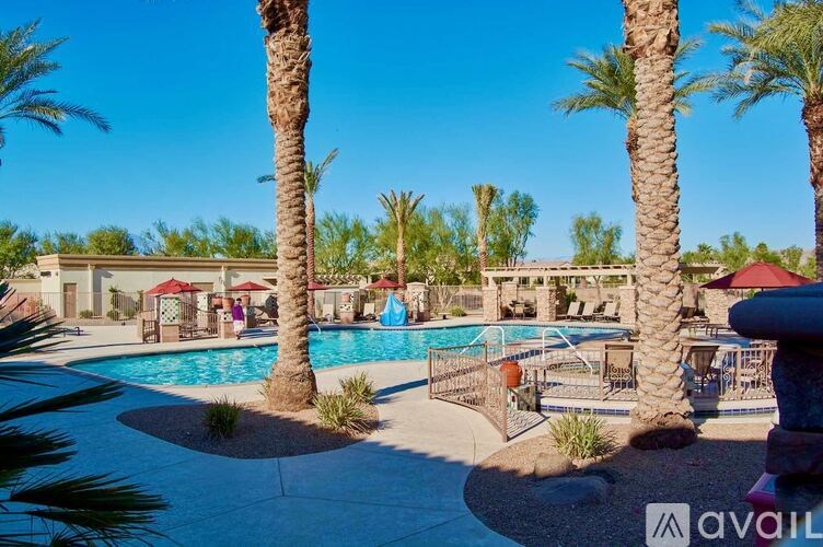 A pool surrounded by palm trees and a red umbrella.