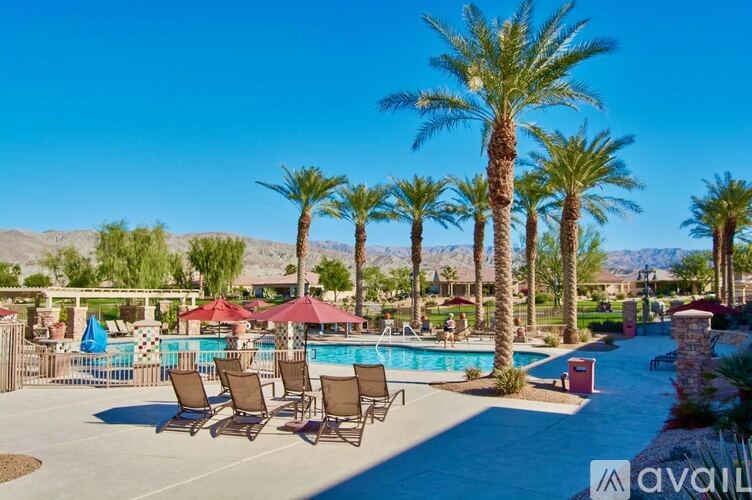 A pool surrounded by palm trees and lounge chairs.