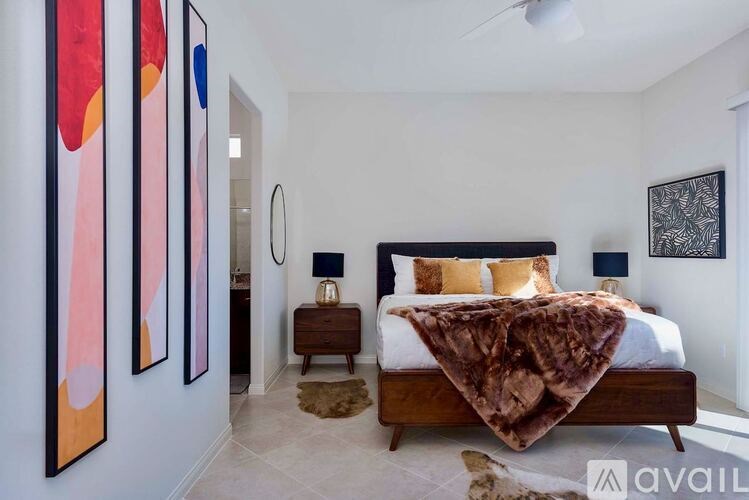 A bedroom with a bed, a nightstand, and three paintings on the wall.
