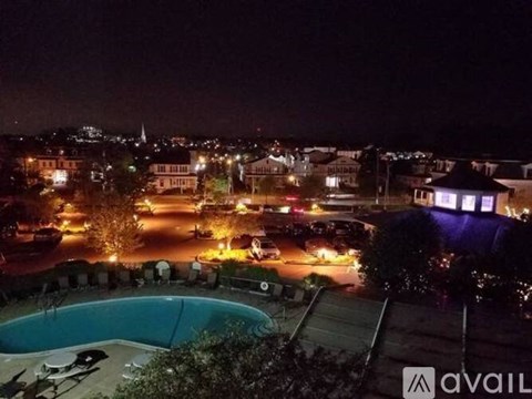 A pool is visible in the foreground of a nighttime cityscape.