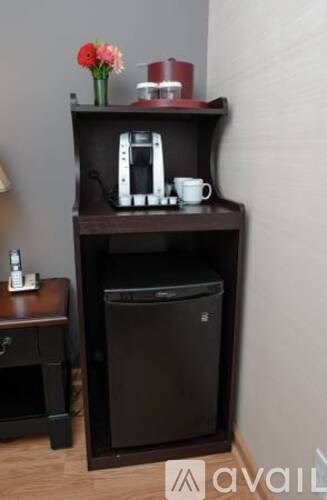 A black cabinet with a coffee maker and a cup on top.