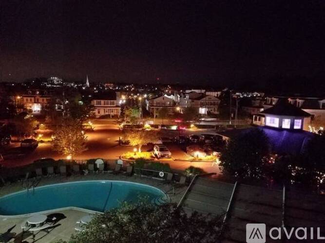 A pool is visible in the foreground of a nighttime cityscape.