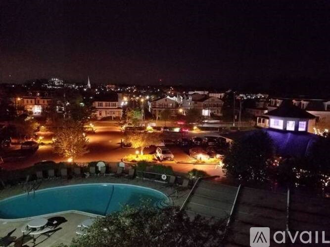 A pool is visible in the foreground of a nighttime cityscape.