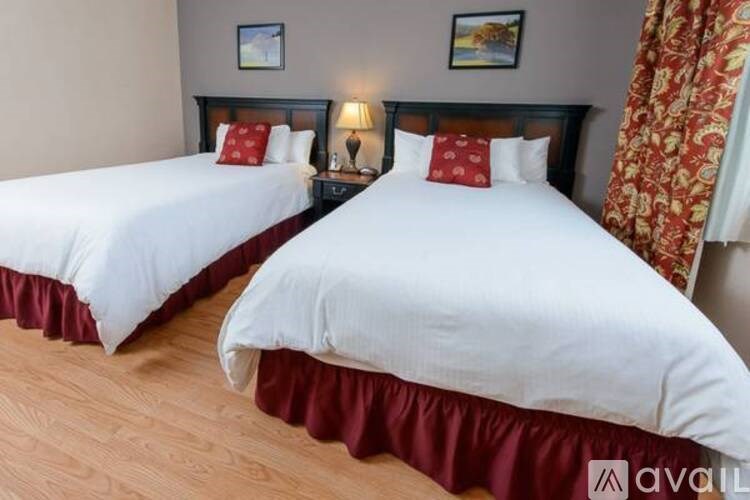 Two twin beds with white bedspreads and red bed skirts in a room.