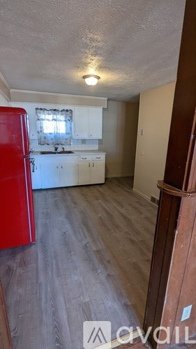 A kitchen with a red fridge and wooden floors.