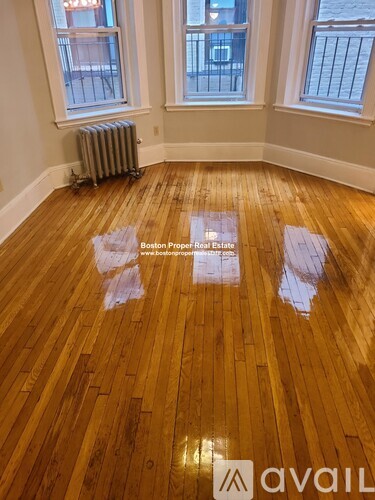 A room with wooden flooring and two windows.