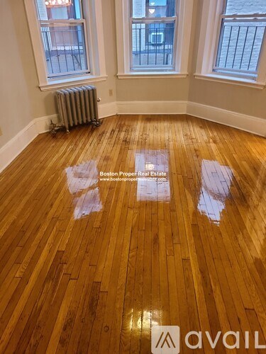A room with wooden flooring and two windows.
