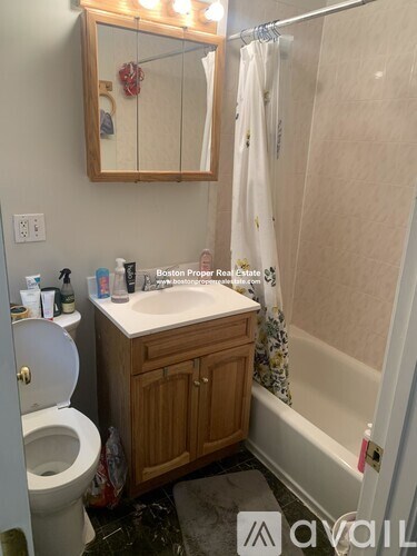 A bathroom with a toilet, sink, and mirror.