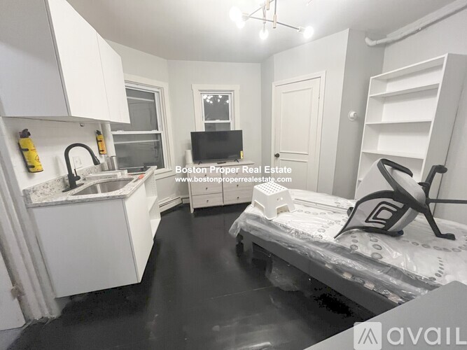 A small, empty room with a bed, sink, and shelves.