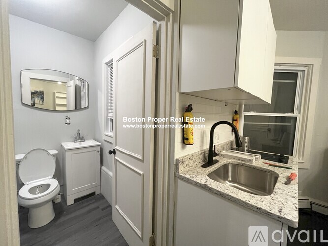 A bathroom with a toilet, sink, and mirror.