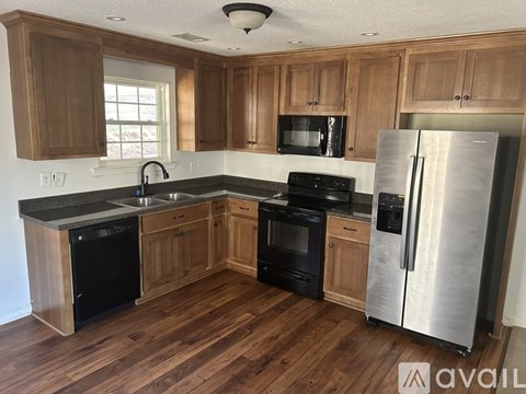 A kitchen with wooden cabinets and a black fridge.