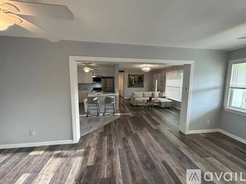 A living room with a kitchen in the background and a dining table in the middle.