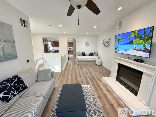 A living room with a white couch and a television on the wall.